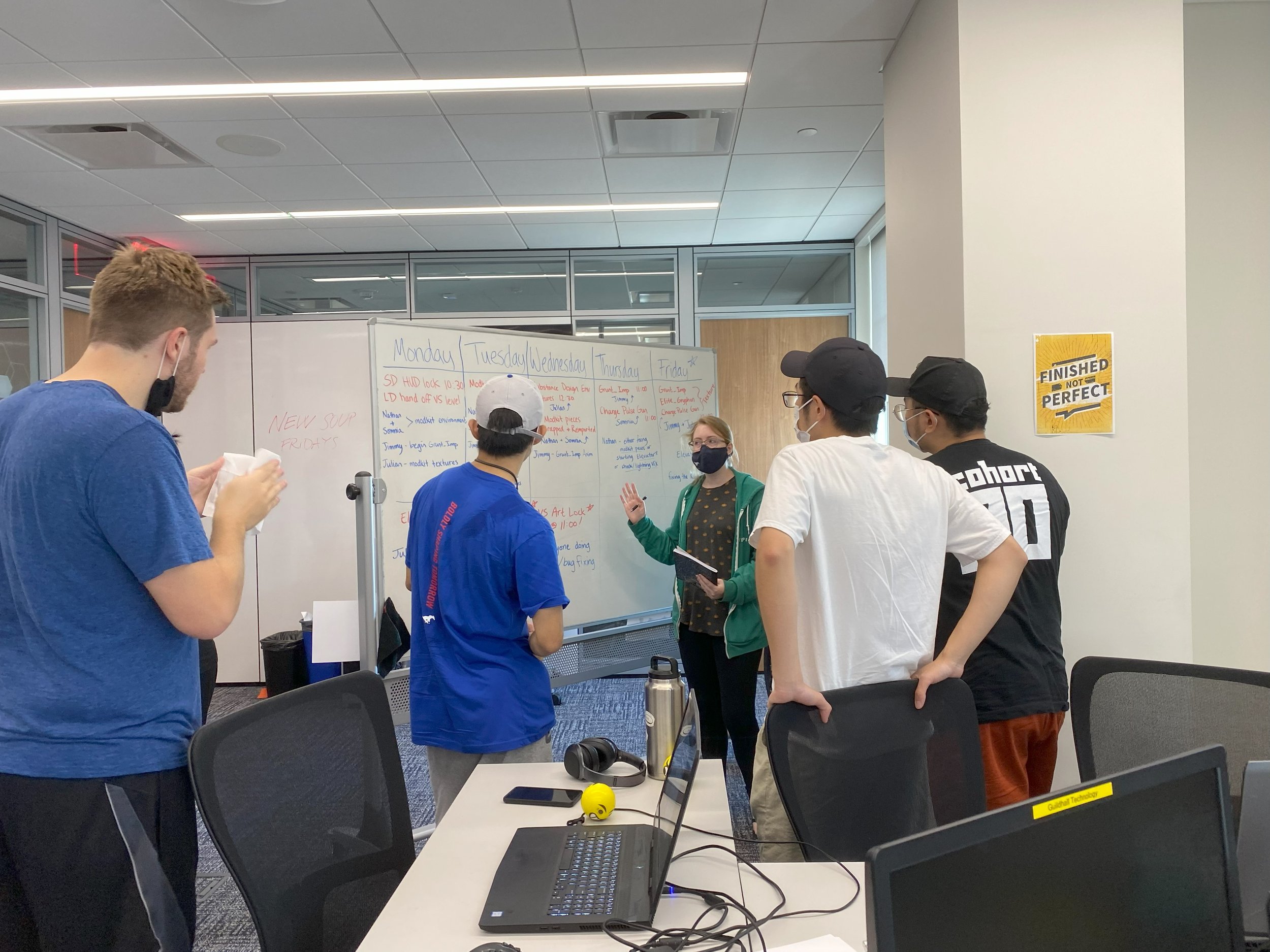 Photo of Dube at whiteboard going over weekly schedule with artists.